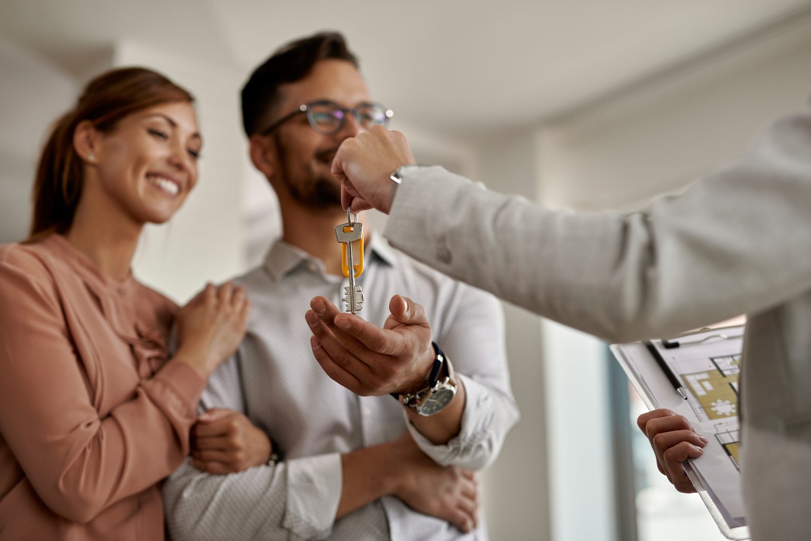 Close-up of a real estate agent giving to a couple keys of their new home.